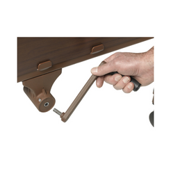 Hand turning the crank handle on a brown wood competitor II semi electric hospital bed by Drive Medical