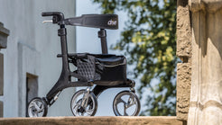 Drive Medical Nitro Elite CF Carbon Fiber Walker Rollator with black seat and storage bag outdoors