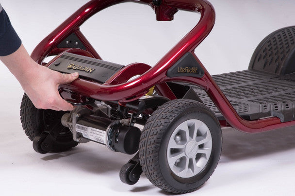 Hand adjusting the base of the LiteRider 3 Wheel Mobility Scooter in vibrant red for easy maneuverability