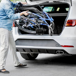 Person loading folded STRONGBACK 24AB Transport Wheelchair 1007AB into the back of a white car